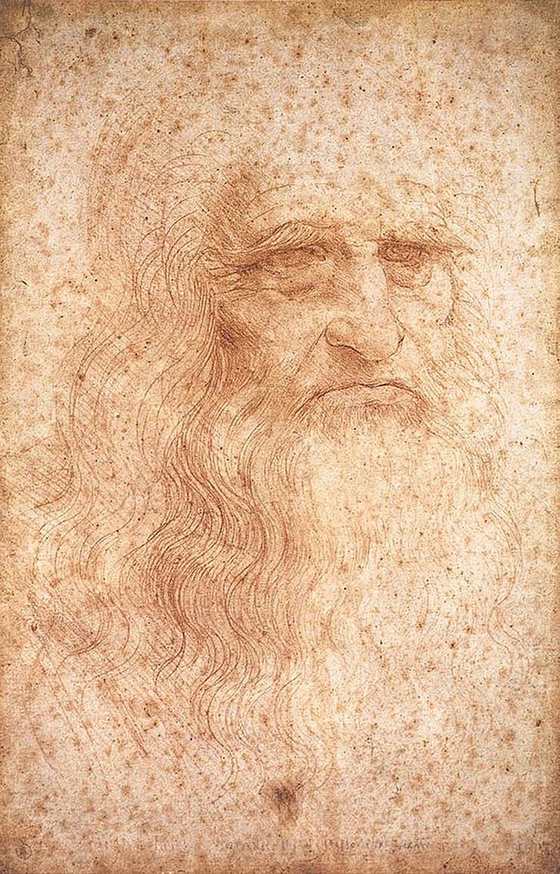 An old man with long flowing hair and beard, heavy brows and a downturned mouth, drawn in red chalk on spotted paper — Leonardo da Vinci, Portrait of a Man in Red Chalk, c. 1512