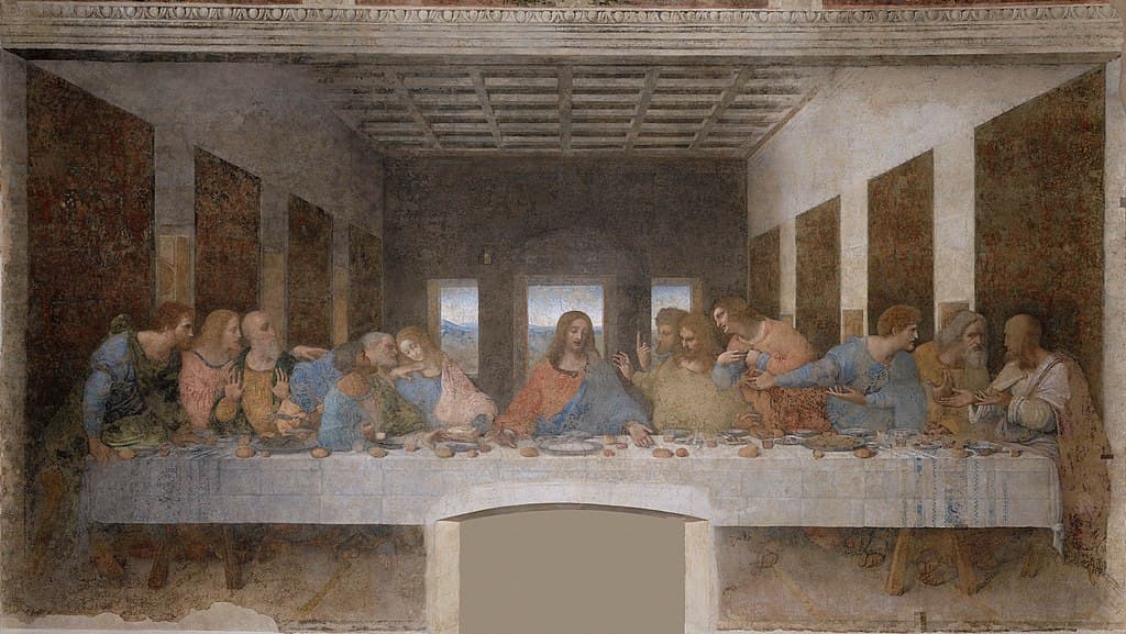 Christ sits at the center of a long white table as twelve apostles react in four agitated groups in a room receding to three windows — Leonardo da Vinci, The Last Supper, c. 1495–98