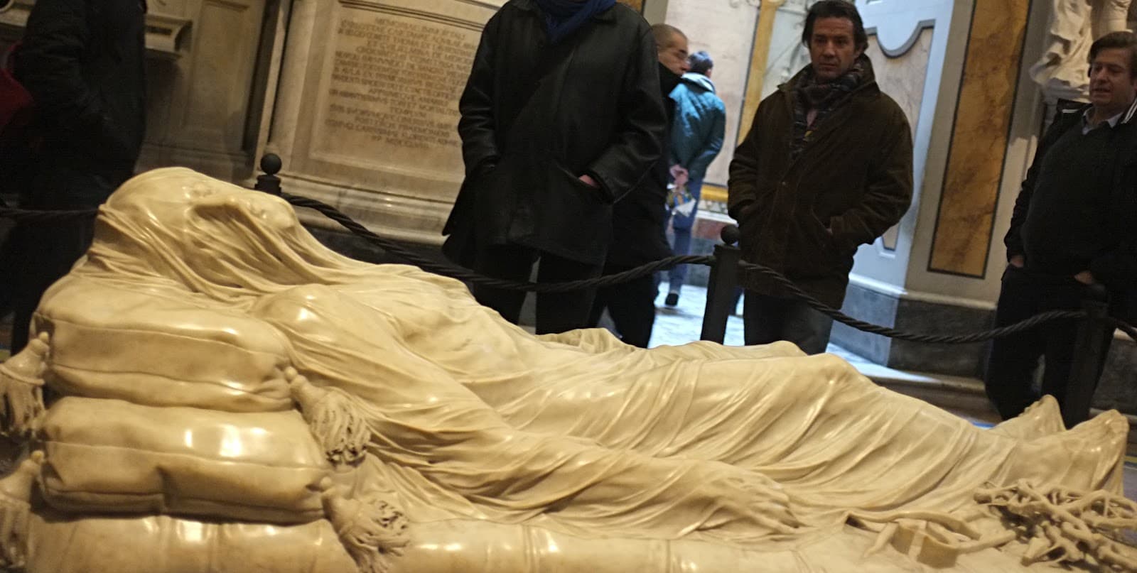 A marble figure of the dead Christ lies on a mattress and cushions under a thin carved veil that reveals his face and body — Giuseppe Sanmartino, Veiled Christ, 1753