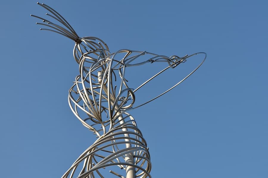 A tall stainless steel figure of a woman made of spiraling bands holds a ring aloft against a clear blue sky — Andy Scott, Beacon of Hope, Belfast, 2007