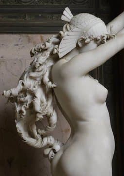 A life-size nude young woman in white marble steps forward with her arms raised and fingers interlaced above her head, lifting her hair, on a tall veined-marble column — Ambrogio Borghi, Berenice's Tresses, 1878