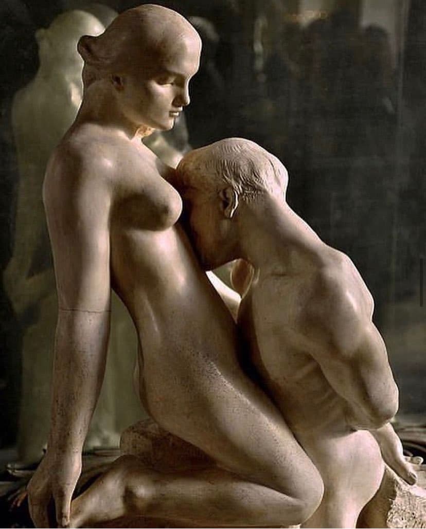 A kneeling nude man with his hands clasped behind his back kisses the body of a nude woman who looks down at him from a rough marble block — Auguste Rodin, The Eternal Idol, c. 1889
