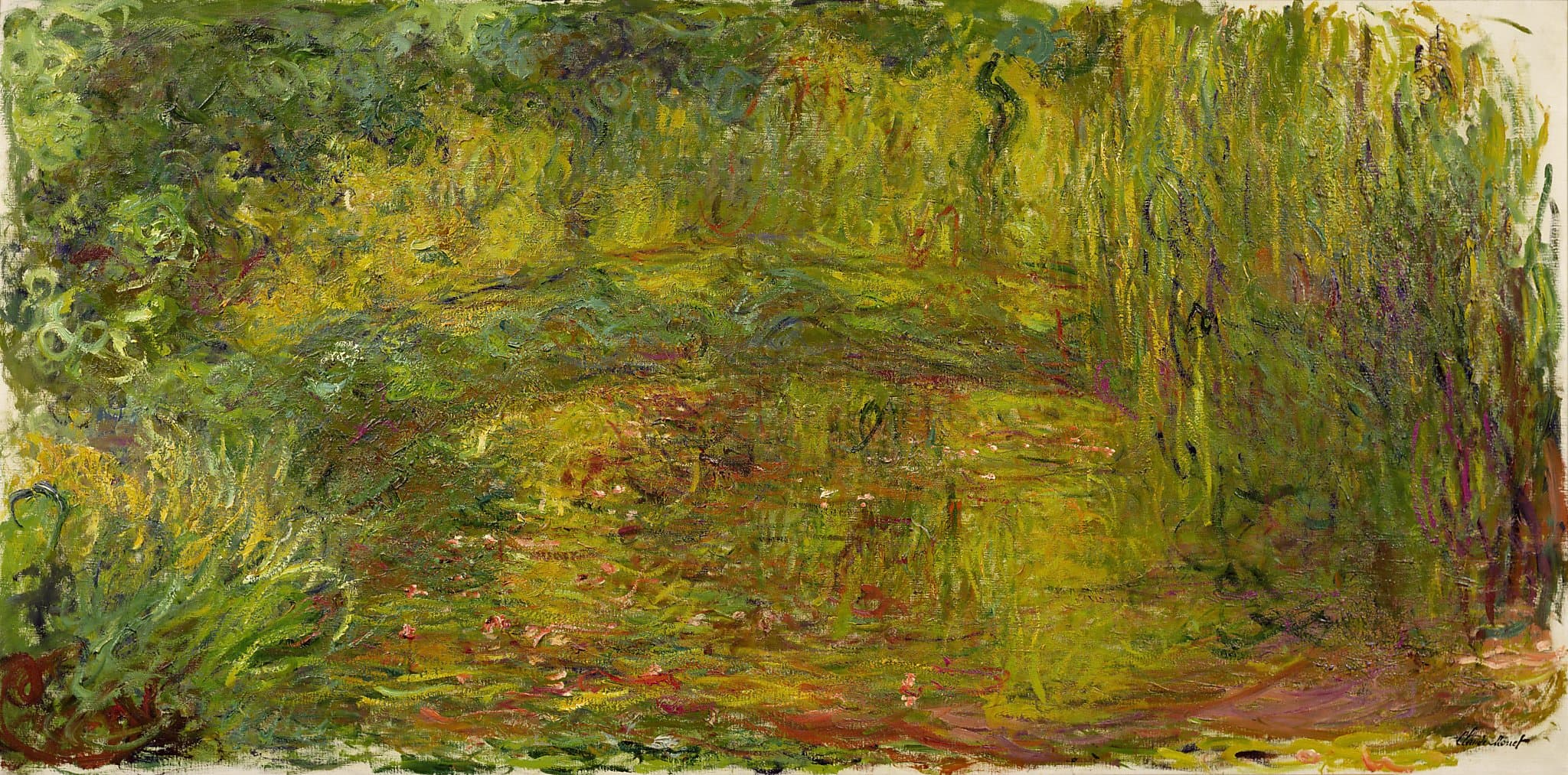 A faint low arch of green crosses a wide canvas of yellow-green foliage, willow fronds hanging at right over a pond dotted with red flowers — Claude Monet, The Japanese Bridge, 1918