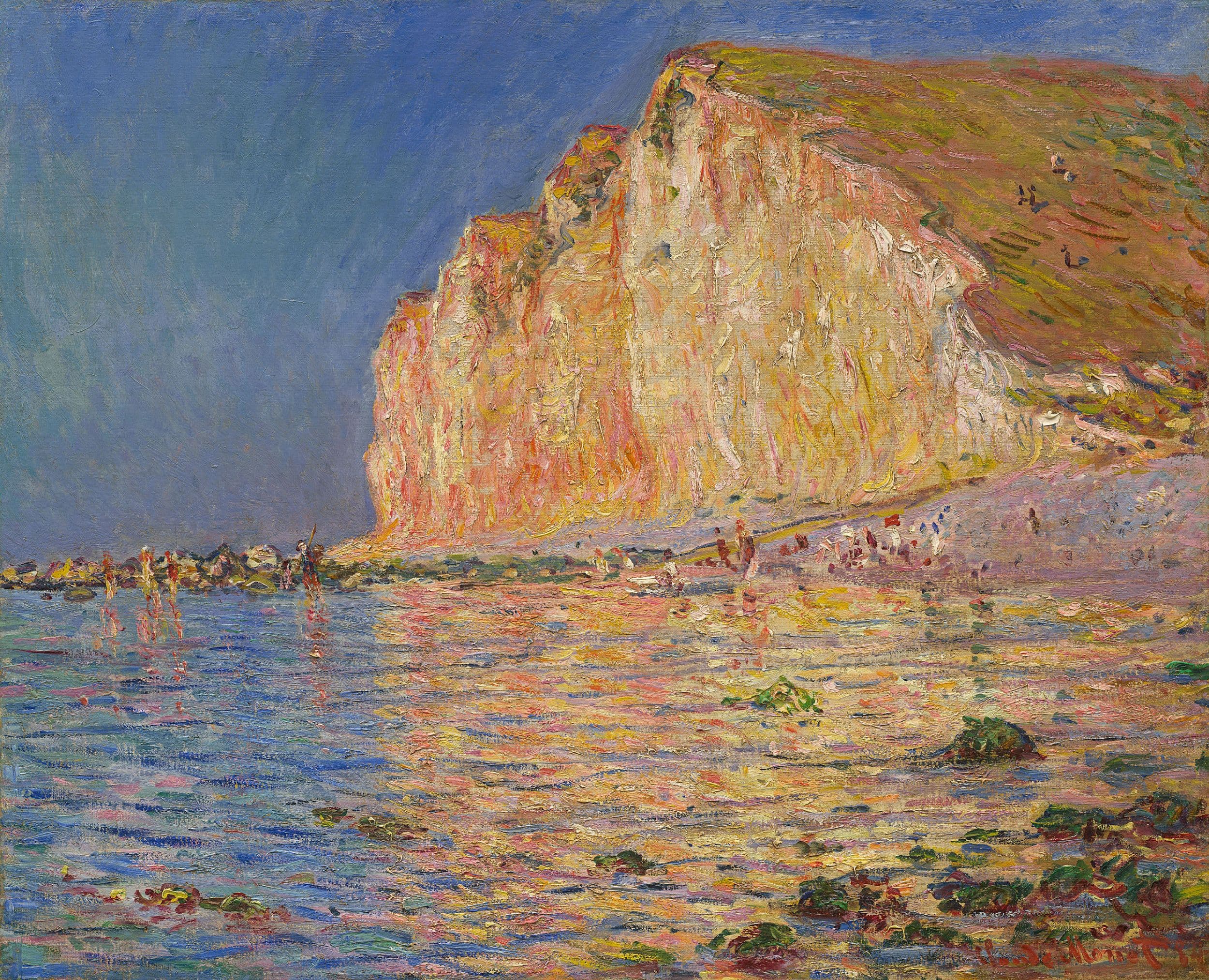 A tall chalk cliff glows orange and pink against a deep blue sky above shallow water full of colored reflections, with tiny bathers along the shore — Claude Monet, Low Tide at Les Petites-Dalles, 1884