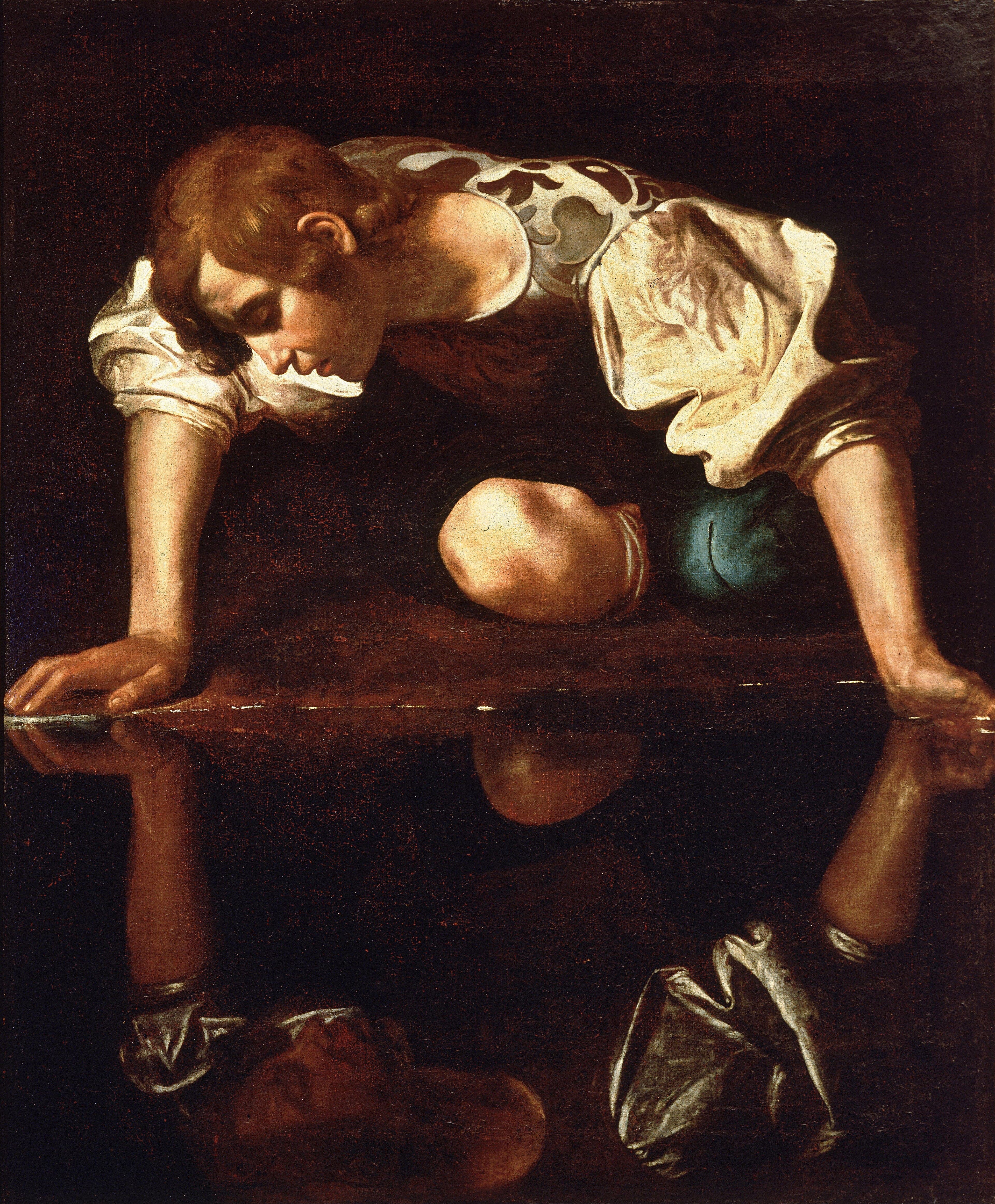 A young man in a brocade doublet kneels and leans over a dark pool, gazing at his upside-down reflection — Caravaggio, Narcissus, c. 1597–99