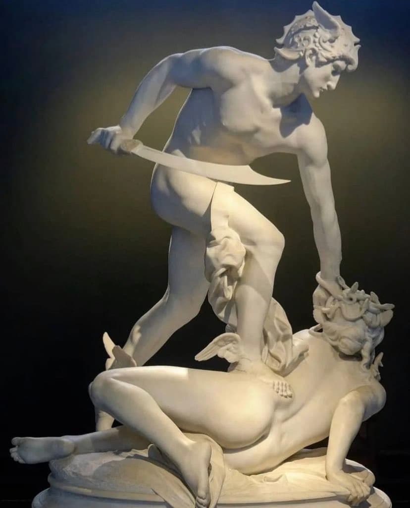 A nude Perseus in a winged helmet pins the fallen, screaming Medusa by her snake-hair and raises a curved sword, in white marble against a dark background — Laurent Marqueste, Perseus and the Gorgon