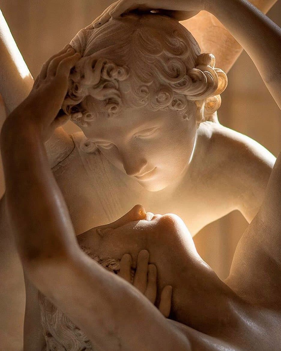 Close view of a marble Cupid with curly hair bending to kiss Psyche, whose hands cradle the back of his head as their lips almost meet — Antonio Canova, Psyche Revived by Cupid's Kiss, 1787–1793