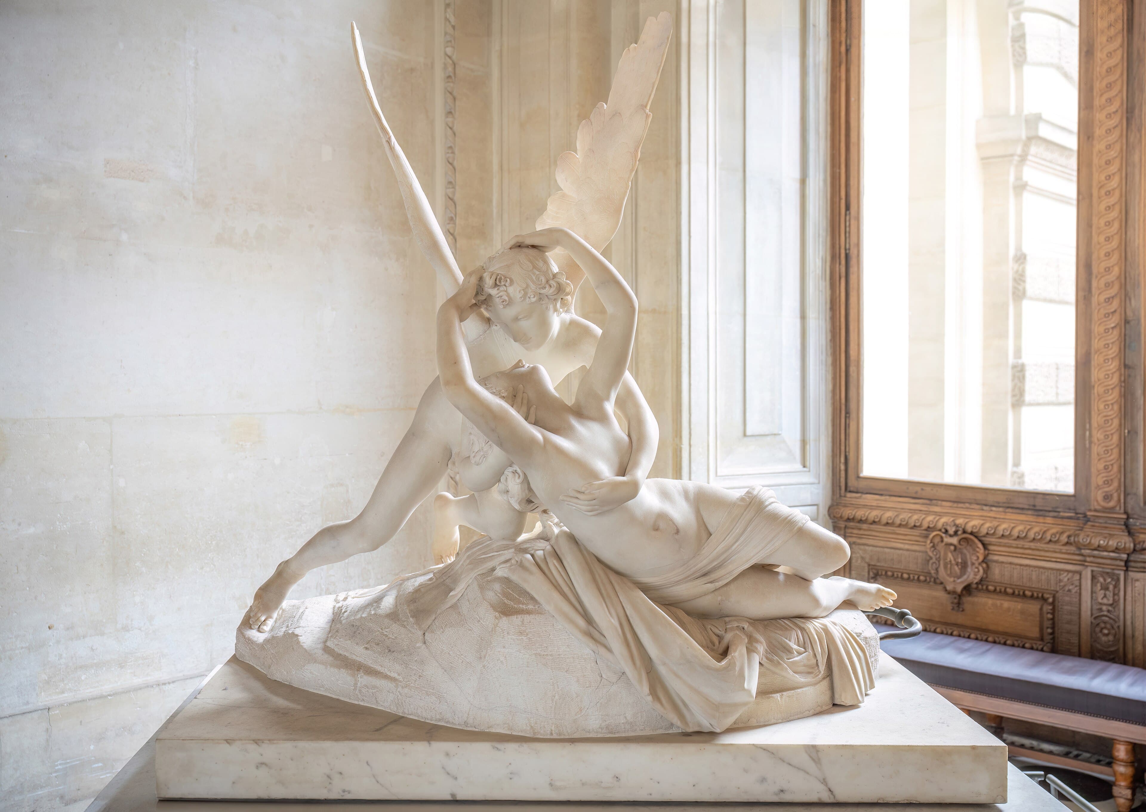 Close view of a marble Cupid with curly hair bending to kiss Psyche, whose hands cradle the back of his head as their lips almost meet — Antonio Canova, Psyche Revived by Cupid's Kiss, 1787–1793