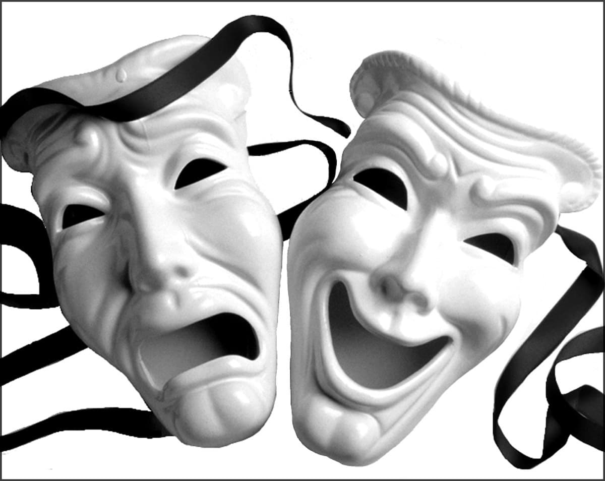 Two white theater masks hang on black ribbons, one weeping with a downturned mouth and one laughing with a wide grin — sock and buskin, the masks of tragedy and comedy
