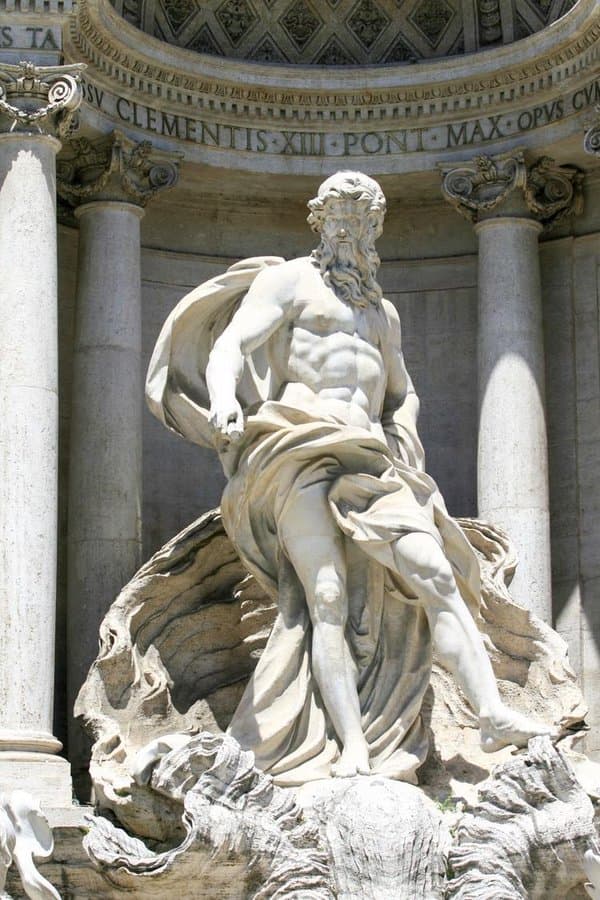 A colossal bearded marble figure with billowing drapery strides forward from a columned niche above carved rocks — Pietro Bracci, Oceanus, Trevi Fountain, Rome, completed 1762