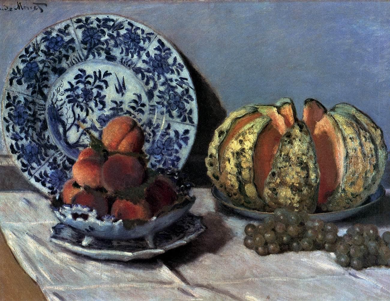 A melon cut into wedges, a bowl of peaches and green grapes sit on a white cloth before an upright blue-and-white porcelain plate — Claude Monet, Still-Life with Melon, c. 1872