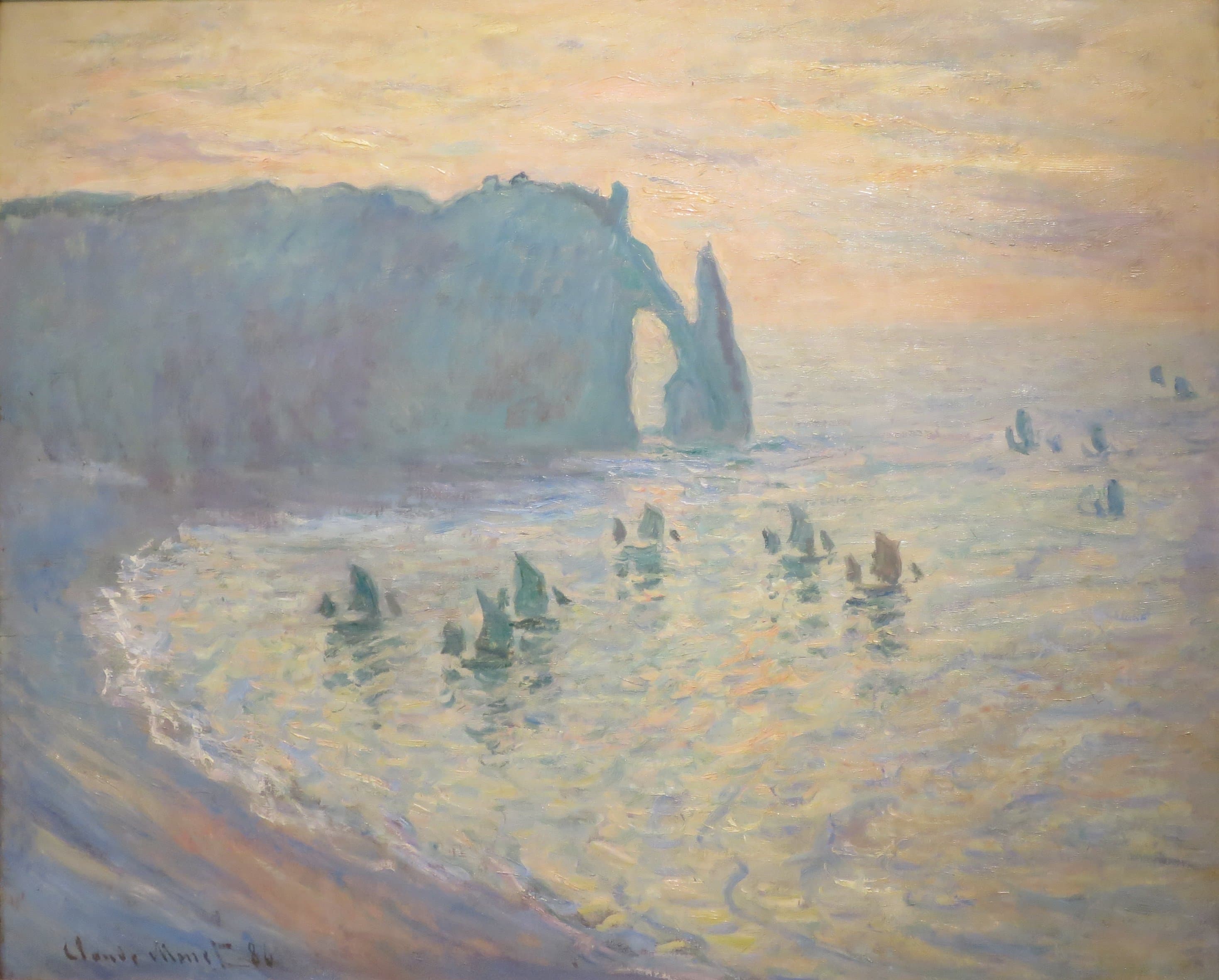 A blue chalk cliff ending in a sea arch and a pointed rock stands against a pink evening sky above a shimmering bay dotted with sailing boats — Claude Monet, The Cliffs at Étretat, 1886