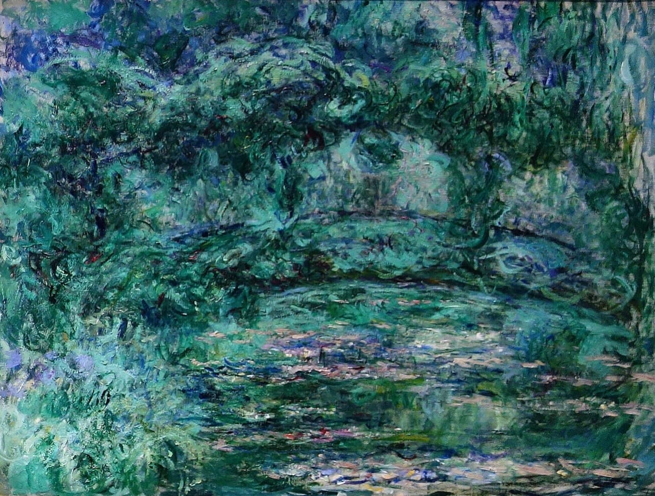 A blue-green arch spans a pond scattered with pale pink lily pads beneath soft turquoise foliage — Claude Monet, The Japanese Bridge, c. 1919–24