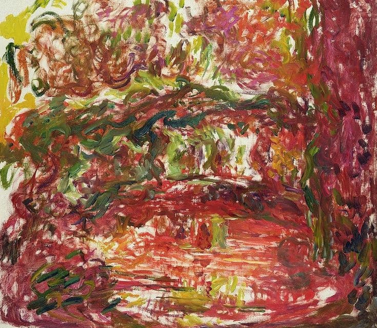 A low red arch under sweeping strokes of vermilion, orange and yellow, with dark green loops of wisteria across it and a glow of light beneath — Claude Monet, The Japanese Bridge, c. 1918–24