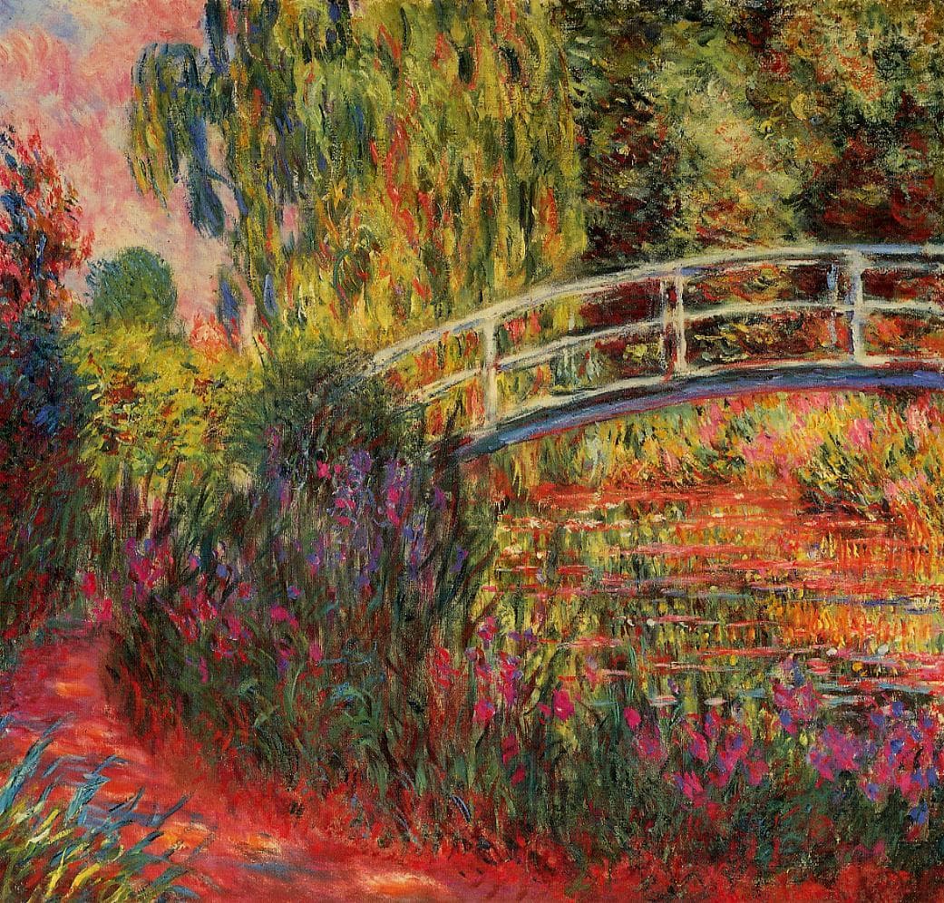 A pale arched footbridge crosses a red-tinted lily pond under a willow, with purple irises and a red path in front — Claude Monet, The Japanese Bridge or The Lily Pond, 1900