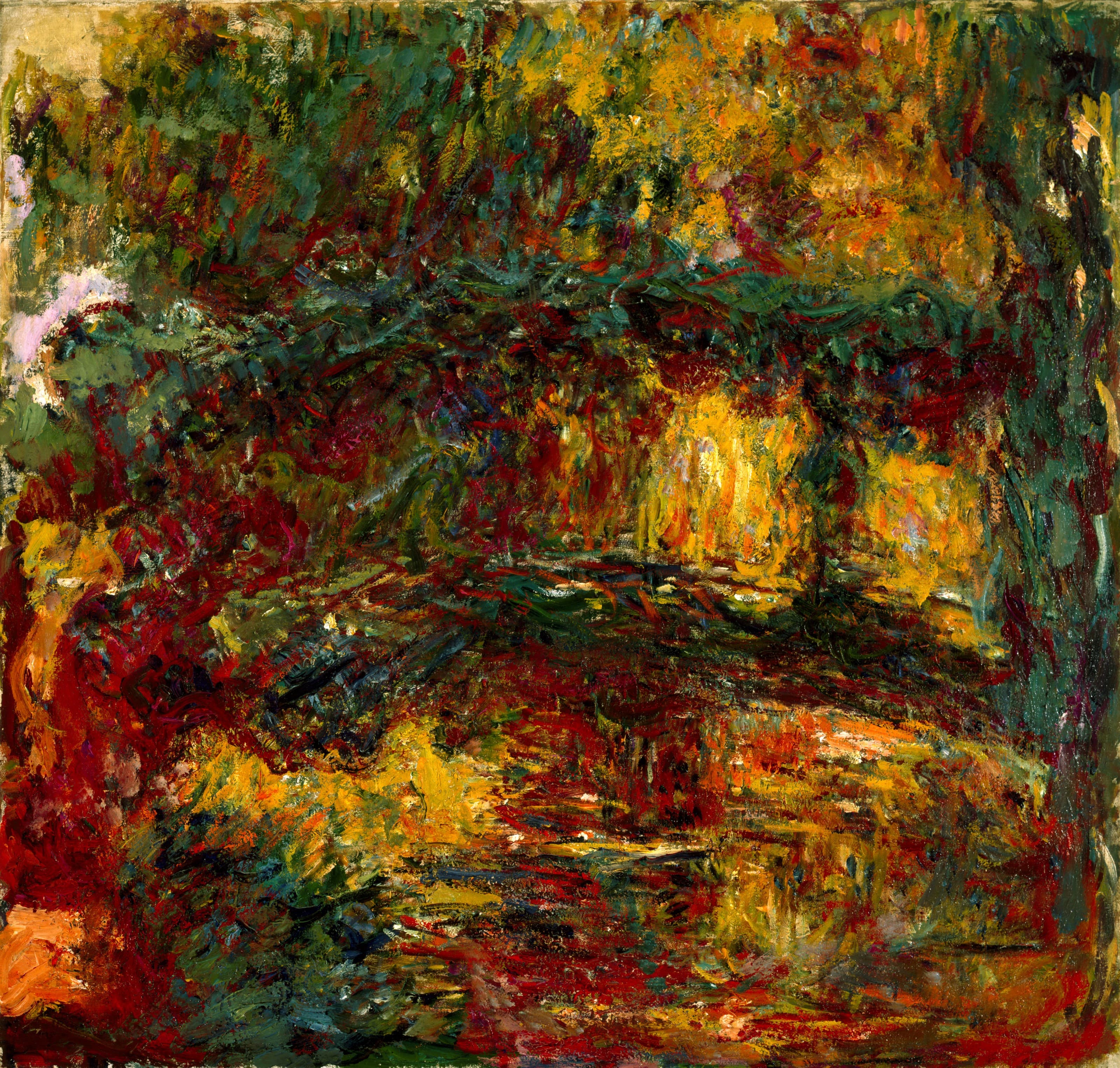 A dark arch in red and green frames a glowing opening of yellow light with willow fronds, reflected in a crimson and gold pond — Claude Monet, The Japanese Footbridge, Giverny, c. 1922
