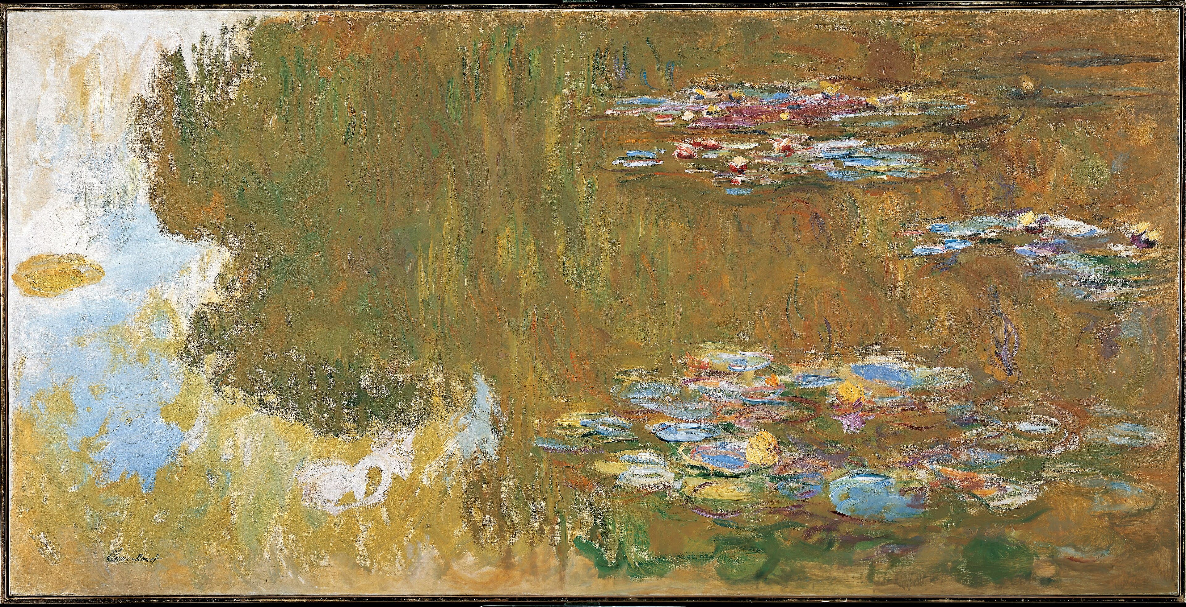 A broad golden-olive reflection of trees fills a pond, with clusters of blue, violet and cream lily pads and pink flowers at the right — Claude Monet, The Water Lily Pond, 1917–19