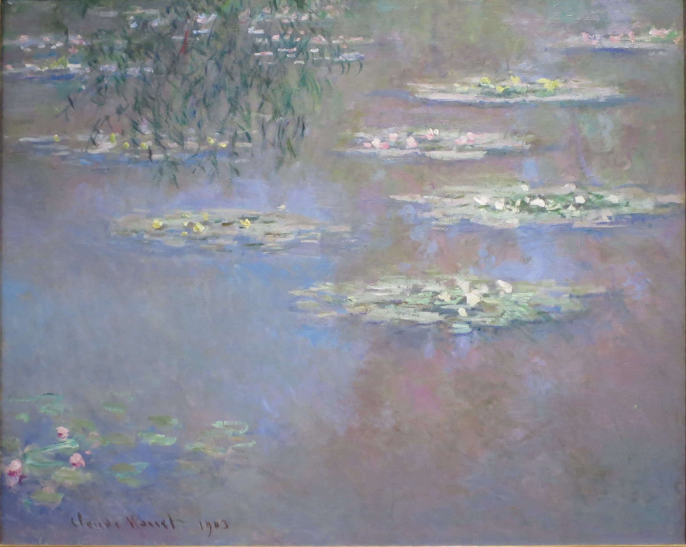 Floating islands of lily pads with white and yellow flowers drift on water reflecting a pink and blue sky, willow fronds hanging at top left — Claude Monet, Waterlilies, 1903