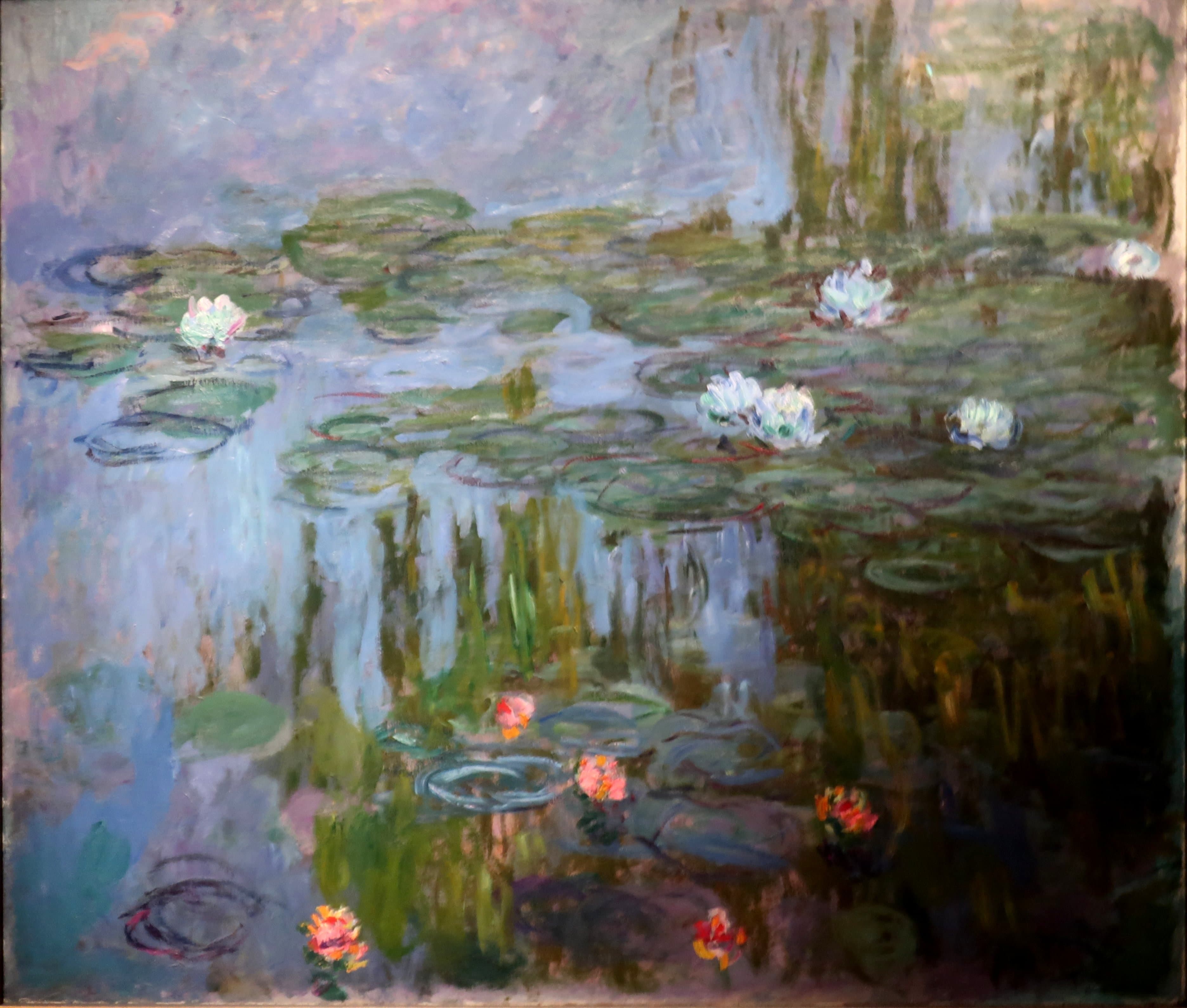 Large white water lilies on gray-green pads and coral-pink blooms float on water reflecting lilac sky and green willows — Claude Monet, Waterlilies, about 1914–15