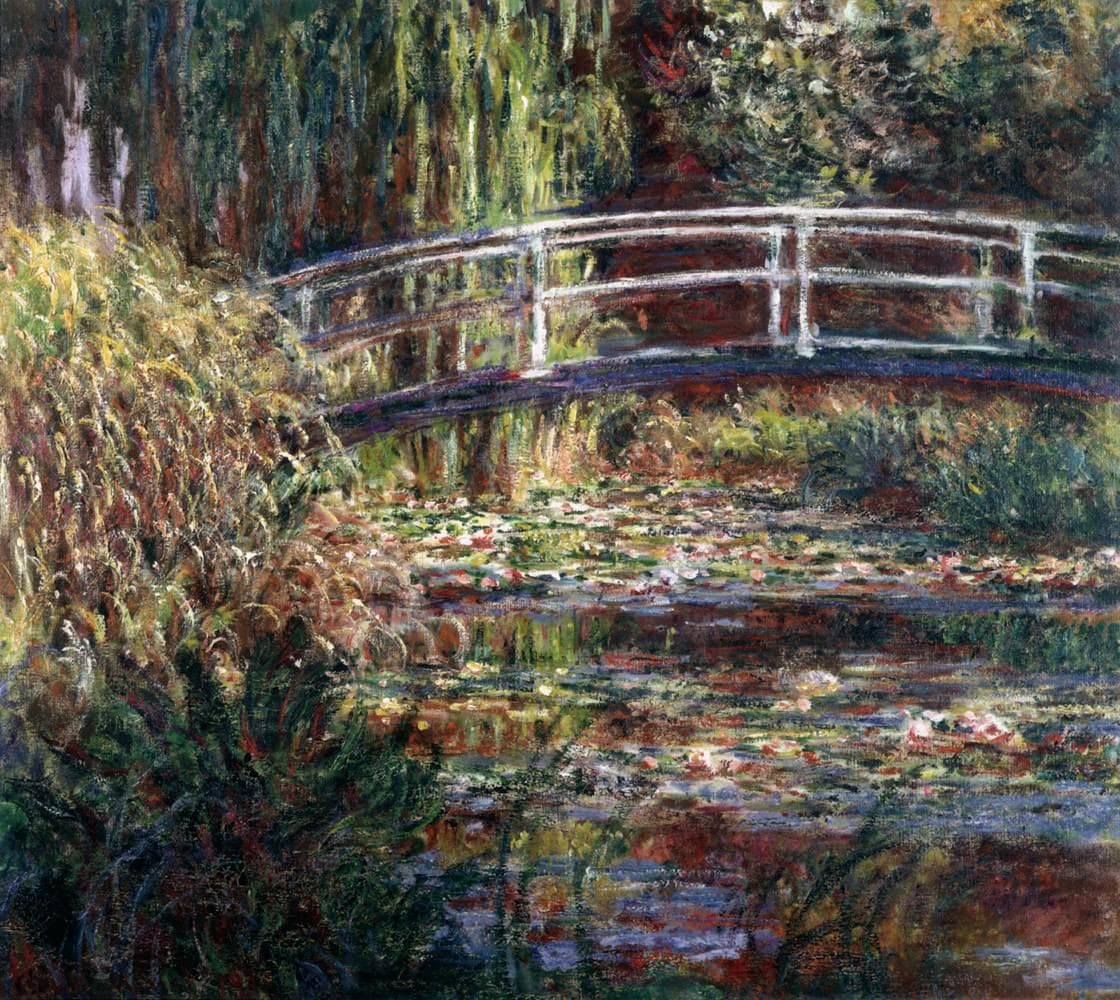 An arched wooden footbridge crosses a pond covered in lily pads under hanging willows, all washed in warm pink and orange light — Claude Monet, The Water Lily Pond, Harmony in Rose, 1900