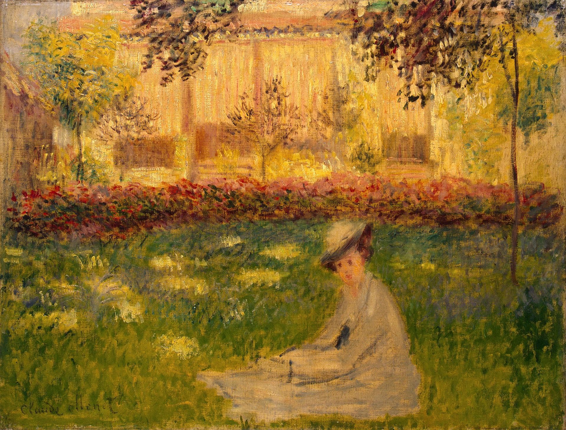 A woman in a pale dress and straw hat sits on a sunlit lawn before a red flowerbed and a glowing yellow building, framed by leaves — Claude Monet, Woman in the Garden, 1876